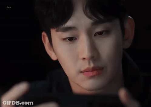 A Close Up Of A Man 'S Face Looking At A Cell Phone . GIF