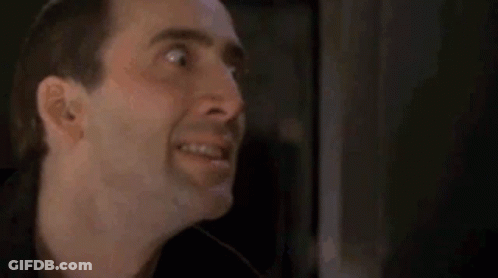 A Close Up Of A Man 'S Face Making A Funny Face In A Dark Room . GIF