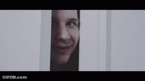 A Close Up Of A Man 'S Face Peeking Out Of A Door . GIF