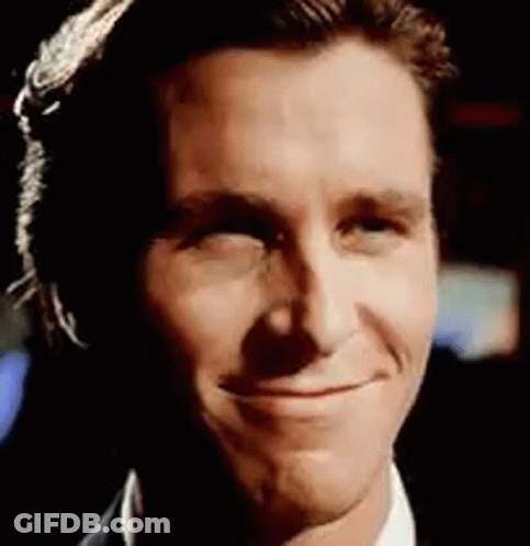 A Close Up Of A Man 'S Face Smiling While Wearing A Suit And Tie . GIF
