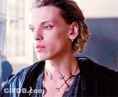 A Close Up Of A Man 'S Face Wearing A Leather Jacket And A Necklace . GIF