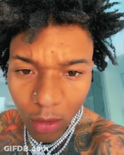 A Close Up Of A Man 'S Face Wearing A Necklace . GIF