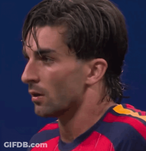 A Close Up Of A Man 'S Face Wearing A Red And Blue Shirt GIF