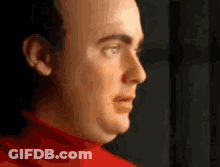 A Close Up Of A Man 'S Face Wearing A Red Sweater . GIF