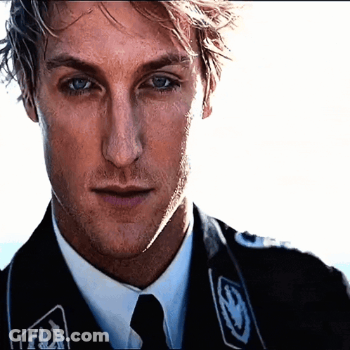 A Close Up Of A Man 'S Face Wearing A Suit And Tie With The Letter S On It GIF