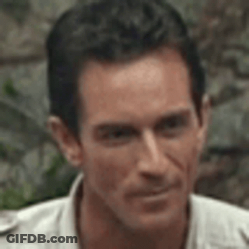 A Close Up Of A Man 'S Face Wearing A White Shirt And Looking At The Camera . GIF