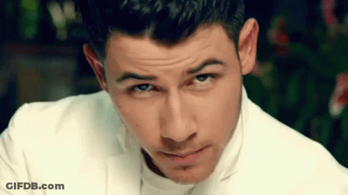 A Close Up Of A Man 'S Face Wearing A White Suit And Looking At The Camera . GIF