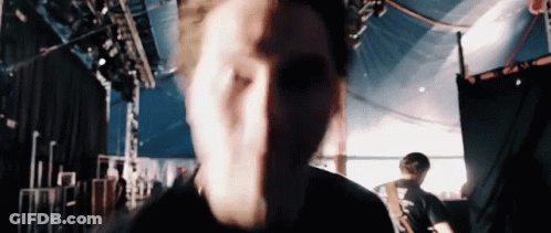 A Close Up Of A Man 'S Face While Playing A Guitar On Stage . GIF