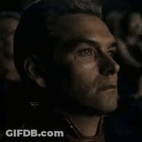 A Close Up Of A Man 'S Face While Watching A Movie In A Dark Room . GIF
