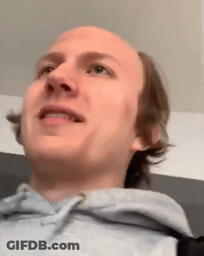 A Close Up Of A Man 'S Face With A Bald Head And A Gray Hoodie . GIF
