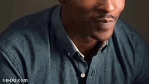 A Close Up Of A Man 'S Face With A Beard And A Blue Shirt . GIF