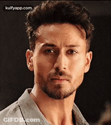 A Close Up Of A Man 'S Face With A Beard And A Gray Shirt . GIF