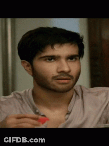 A Close Up Of A Man 'S Face With A Beard And A Pink Shirt GIF