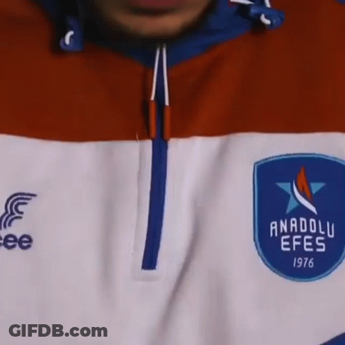 A Close Up Of A Man 'S Face With A Beard And Curly Hair Wearing A Blue And Red Jacket . GIF