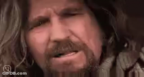 A Close Up Of A Man 'S Face With A Beard And Long Hair Making A Funny Face . GIF