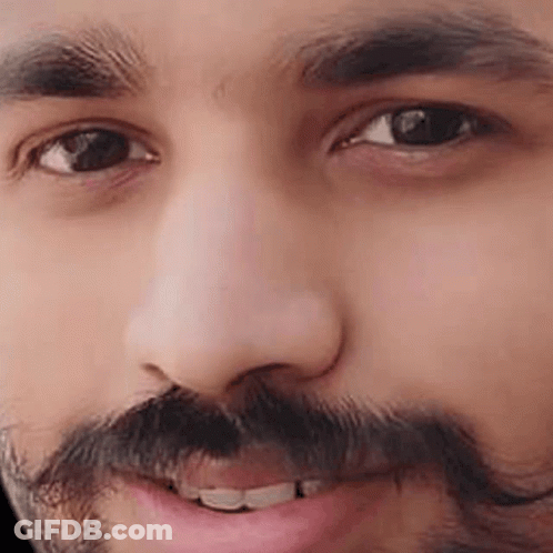 A Close Up Of A Man 'S Face With A Beard And Mustache Smiling . GIF