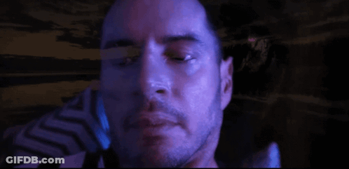 A Close Up Of A Man 'S Face With A Beard In A Dark Room GIF