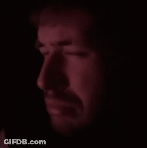 A Close Up Of A Man 'S Face With A Beard In The Dark GIF