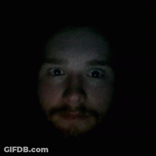 A Close Up Of A Man 'S Face With A Beard In The Dark GIF