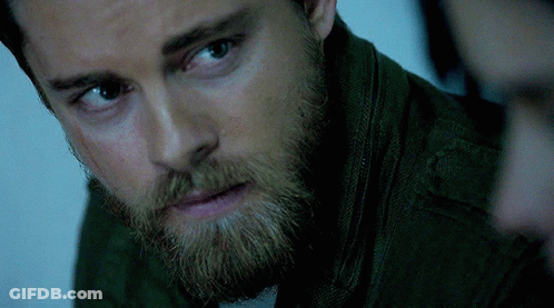 A Close Up Of A Man 'S Face With A Beard Wearing A Green Jacket GIF