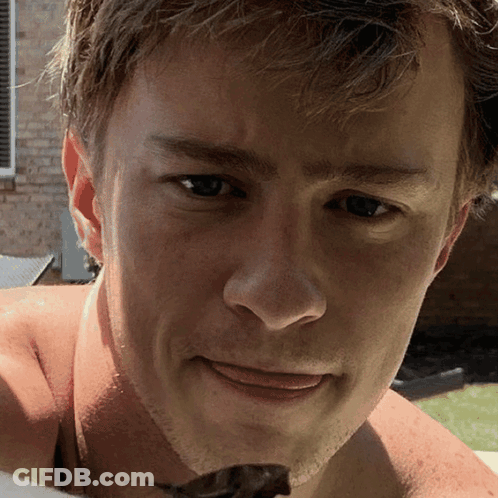 A Close Up Of A Man 'S Face With A Brick Building In The Background GIF