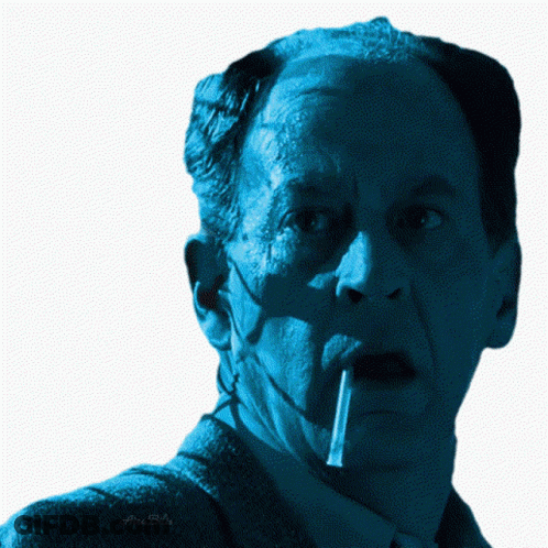A Close Up Of A Man 'S Face With A Cigarette In His Mouth And A Watermark That Says Alex Bello GIF