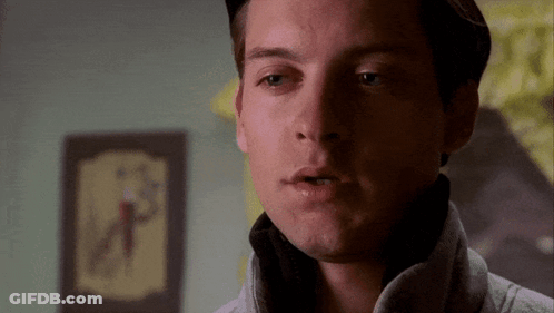 A Close Up Of A Man 'S Face With A Clock On The Wall Behind Him GIF