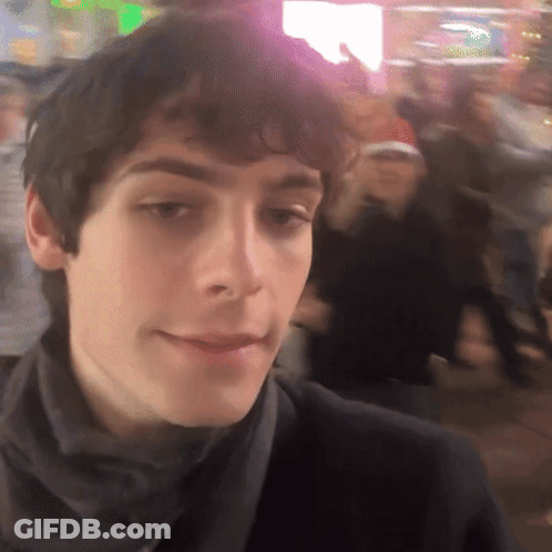 A Close Up Of A Man 'S Face With A Crowd In The Background GIF