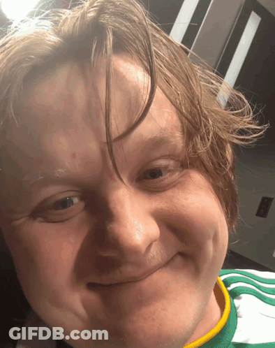 A Close Up Of A Man 'S Face With A Green And Yellow Shirt On GIF
