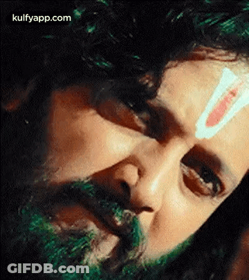 A Close Up Of A Man 'S Face With A Green Beard And A Red And White Stripe On His Forehead . GIF