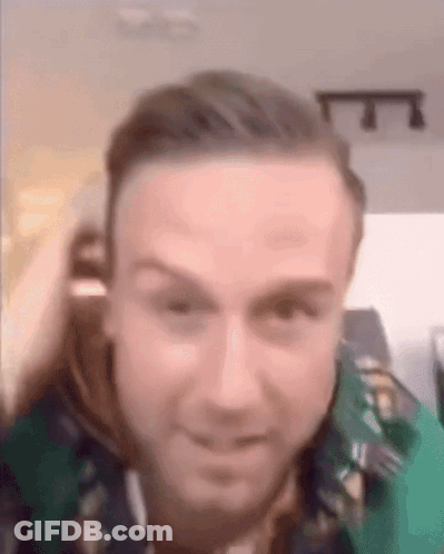 A Close Up Of A Man 'S Face With A Green Shirt On And A Blurred Background . GIF
