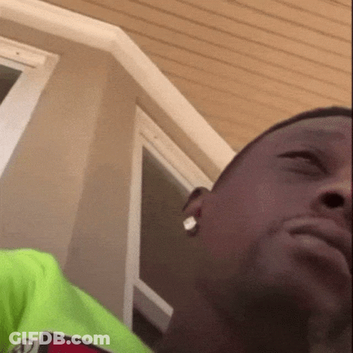 A Close Up Of A Man 'S Face With A Green Shirt On And Earrings . GIF