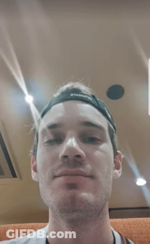 A Close Up Of A Man 'S Face With A Hat On And A Camera Around His Neck . GIF