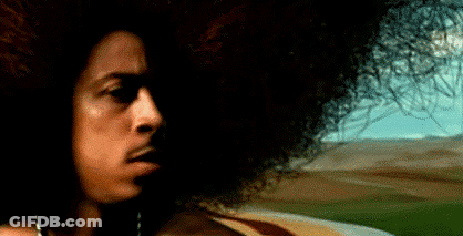 A Close Up Of A Man 'S Face With A Large Afro In Front Of A Field . GIF
