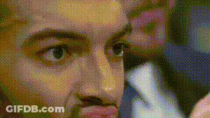 A Close Up Of A Man 'S Face With A Man In A Suit And Tie Behind Him . GIF