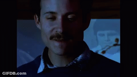 A Close Up Of A Man 'S Face With A Mustache And A Blue Shirt GIF