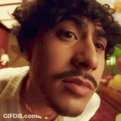 A Close Up Of A Man 'S Face With A Mustache And Curly Hair . GIF