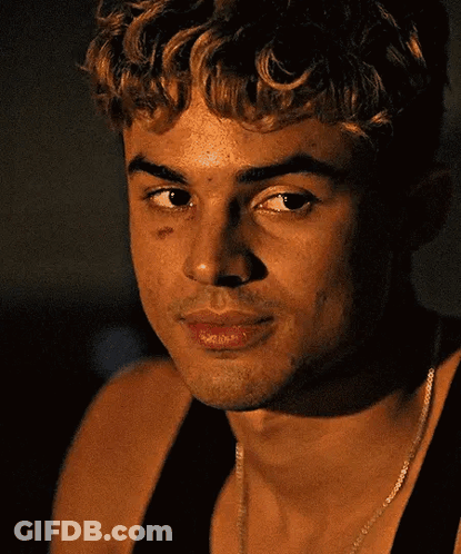 A Close Up Of A Man 'S Face With A Necklace Around His Neck And A Black Tank Top . GIF