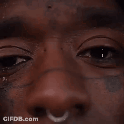 A Close Up Of A Man 'S Face With A Nose Ring And A Tear Running Down His Face . GIF