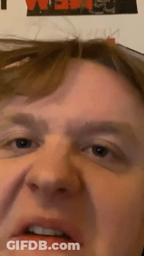 A Close Up Of A Man 'S Face With A Poster In The Background That Says ' We ' GIF
