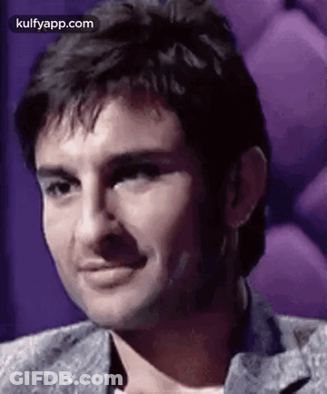 A Close Up Of A Man 'S Face With A Purple Background And A Smile . GIF