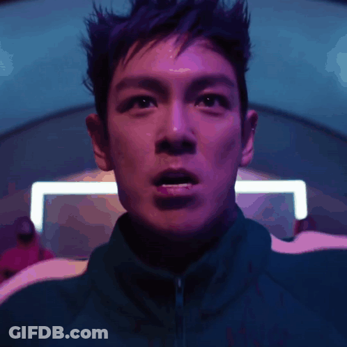 A Close Up Of A Man 'S Face With A Purple Light Behind Him GIF