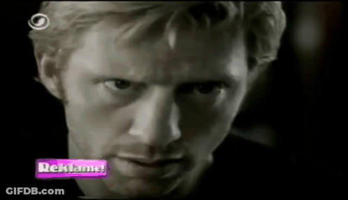 A Close Up Of A Man 'S Face With A Purple Sign That Says Reklama GIF