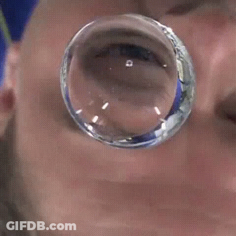 A Close Up Of A Man 'S Face With A Reflection Of Him In A Glass Ball GIF