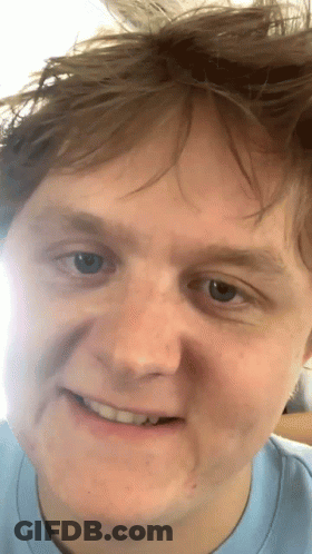 A Close Up Of A Man 'S Face With A Slight Smile On His Face GIF
