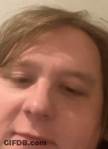 A Close Up Of A Man 'S Face With A Slight Smile On His Face GIF