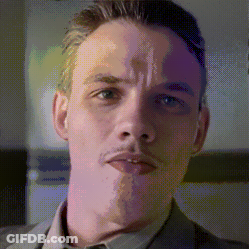 A Close Up Of A Man 'S Face With A Slight Smirk On His Face GIF