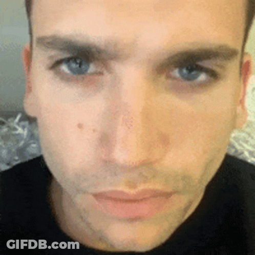 A Close Up Of A Man 'S Face With Blue Eyes And A Black Shirt On GIF