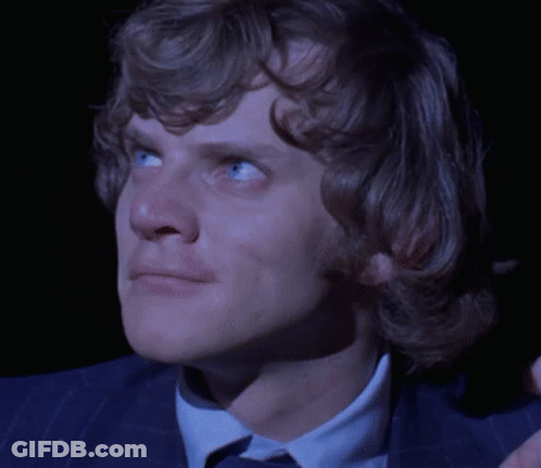 A Close Up Of A Man 'S Face With Blue Eyes And A Blue Suit GIF