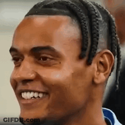 A Close Up Of A Man 'S Face With Braids And A Beard Smiling . GIF